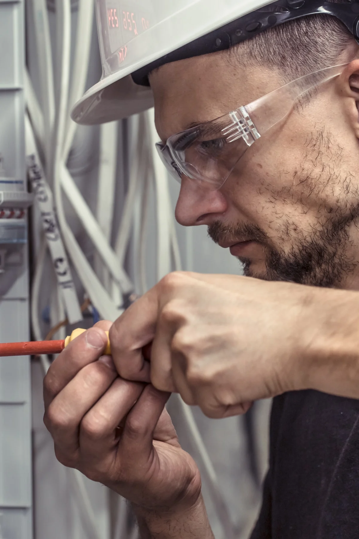 a male electrician works in a switchboard with an electrical con