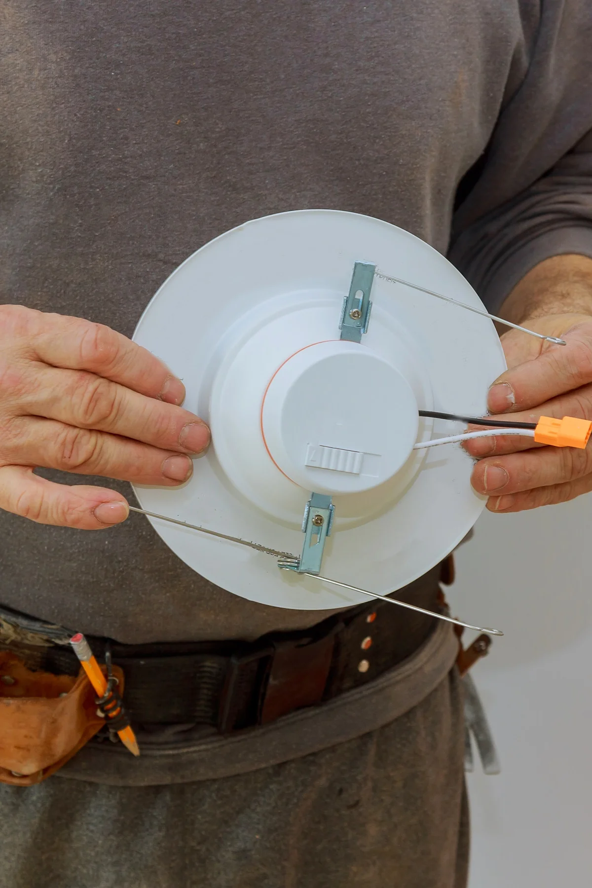 Man is installing electrical light in the ceiling replacing repair works in the flat.